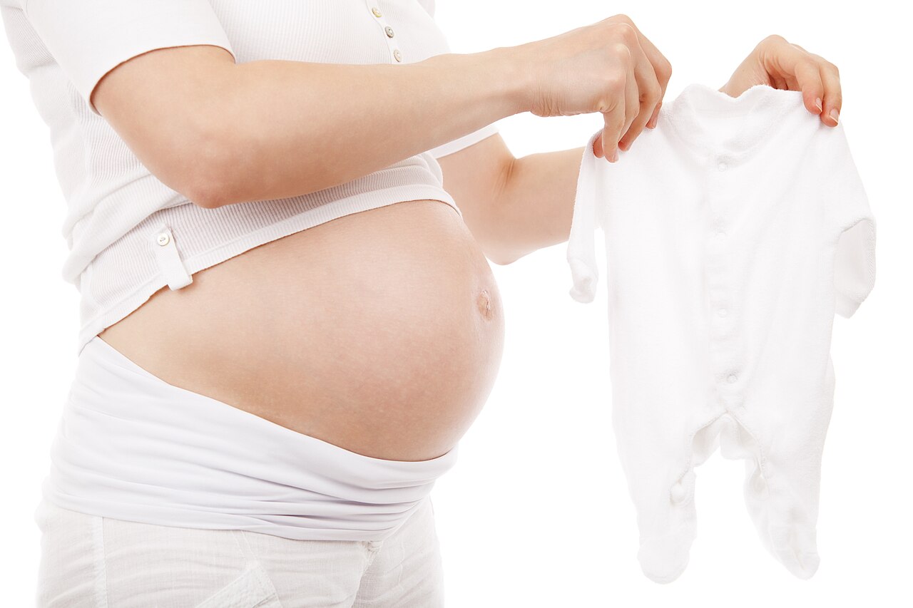 Pregnant person holding a baby sleeper